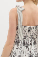 Floral print shoulder tie babydoll dress pullover mini dress featuring stripe pattern border hem. Elasticated smocking at back. Pockets at side.