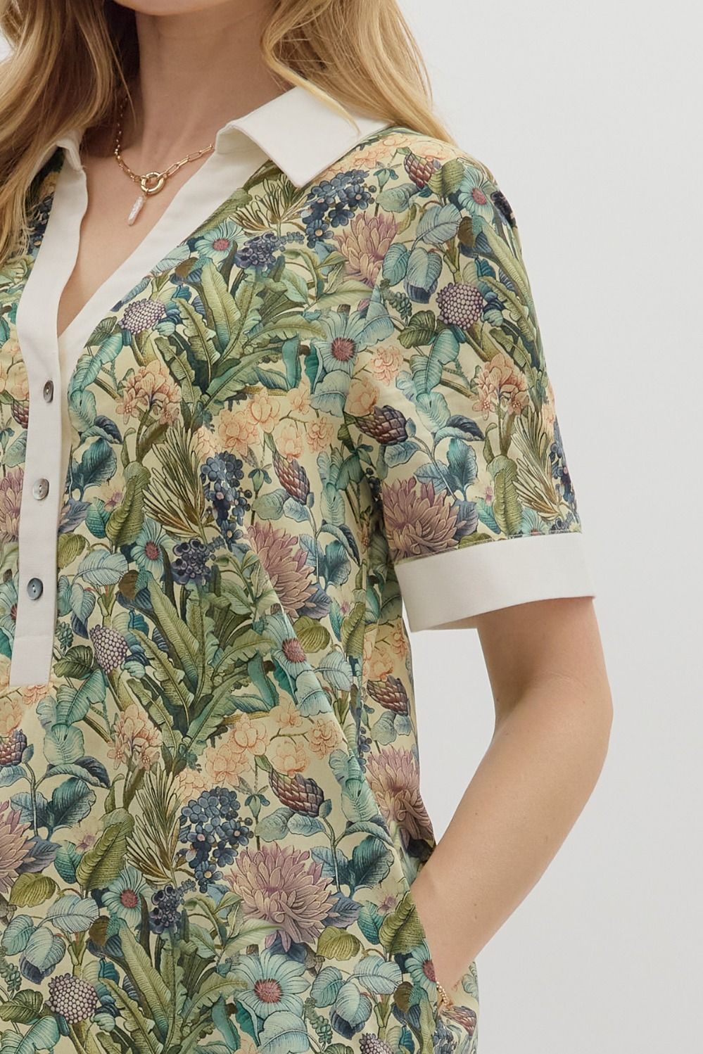 Floral print short sleeve mini dress featuring contrast accent collar button closure and band detail. Pockets at
