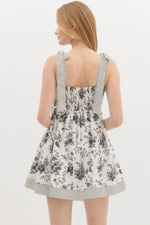 Floral print shoulder tie babydoll dress pullover mini dress featuring stripe pattern border hem. Elasticated smocking at back. Pockets at side.