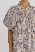 Floral print v-neck bubble sleeve collared midi dress featuring smocking and button detail at front. Slit at sides. Hook and eye closure at front. Elastic at cuff.