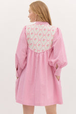 Striped ¾ button closure cuff sleeve pullover mini dress featuring accented floral ribbon pattern yoke. Front neck band tie closure. Pockets at side. Lined.