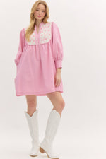 Striped ¾ button closure cuff sleeve pullover mini dress featuring accented floral ribbon pattern yoke. Front neck band tie closure. Pockets at side. Lined.