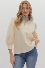 Solid ¾ balloon sleeve popover top featuring contrast ruffle neck. Half button front closure.
