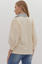 Solid ¾ balloon sleeve popover top featuring contrast ruffle neck. Half button front closure.