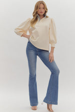 Solid ¾ balloon sleeve popover top featuring contrast ruffle neck. Half button front closure.