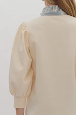 Solid ¾ balloon sleeve popover top featuring contrast ruffle neck. Half button front closure.
