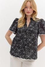 Floral print split v-neck pullover top featuring accented scallop pattern binding finish short sleeve and hem.