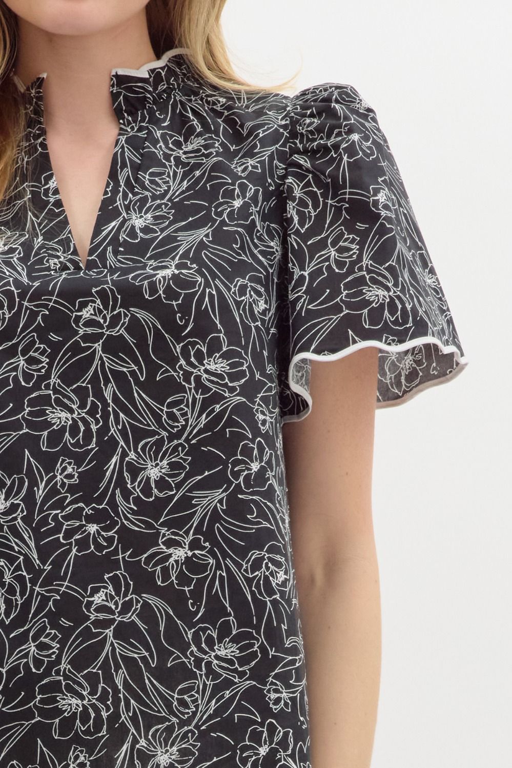 Floral print split v-neck pullover top featuring accented scallop pattern binding finish short sleeve and hem.